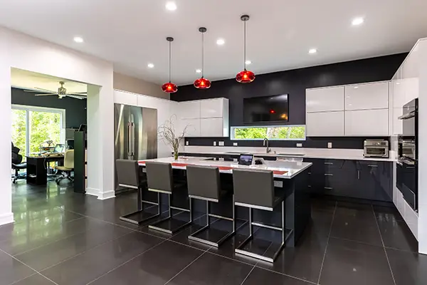 Stunning contemporary kitchen remodel with bold black and white cabinetry, a spacious island, and striking red pendant lighting. Designed by a premier local kitchen remodeling company serving Raleigh, North Carolina, to elevate your home with modern elegance!